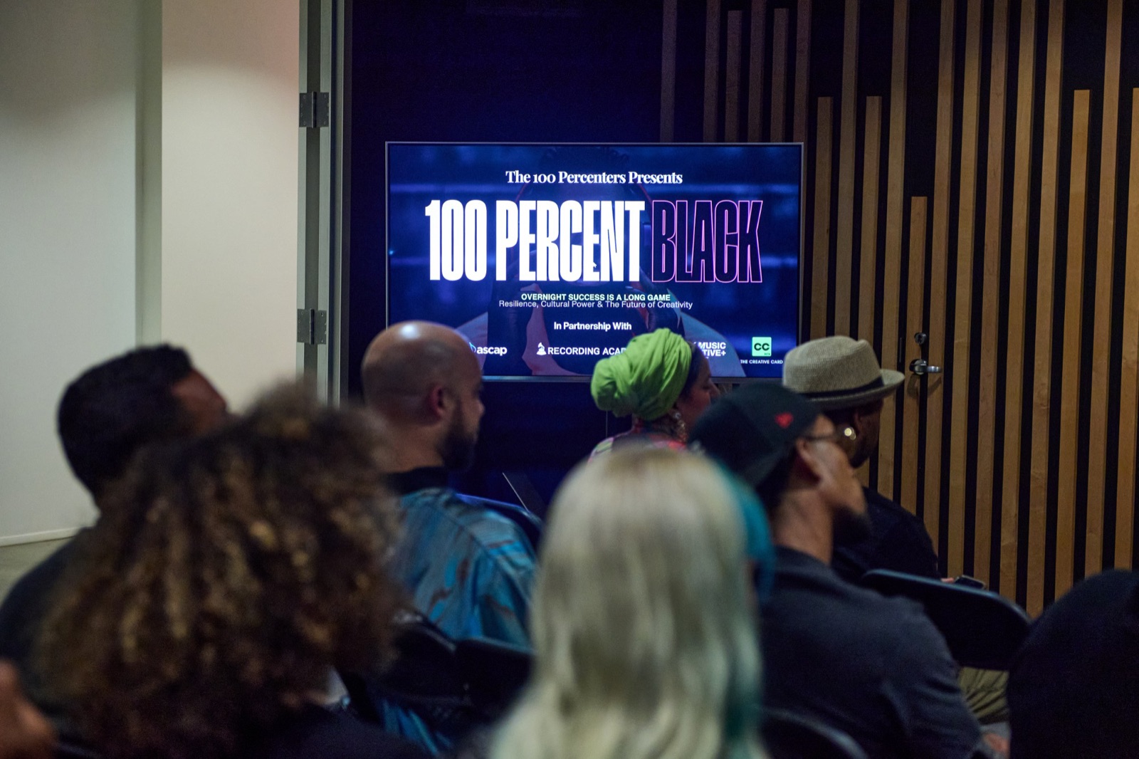 The audience facing a screen that reads 100 Percent BLACK