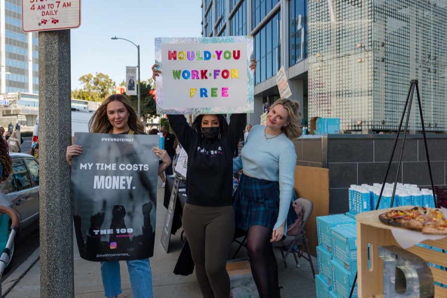 Creators holding signs reading “My time costs money” and “Would you work for free?”